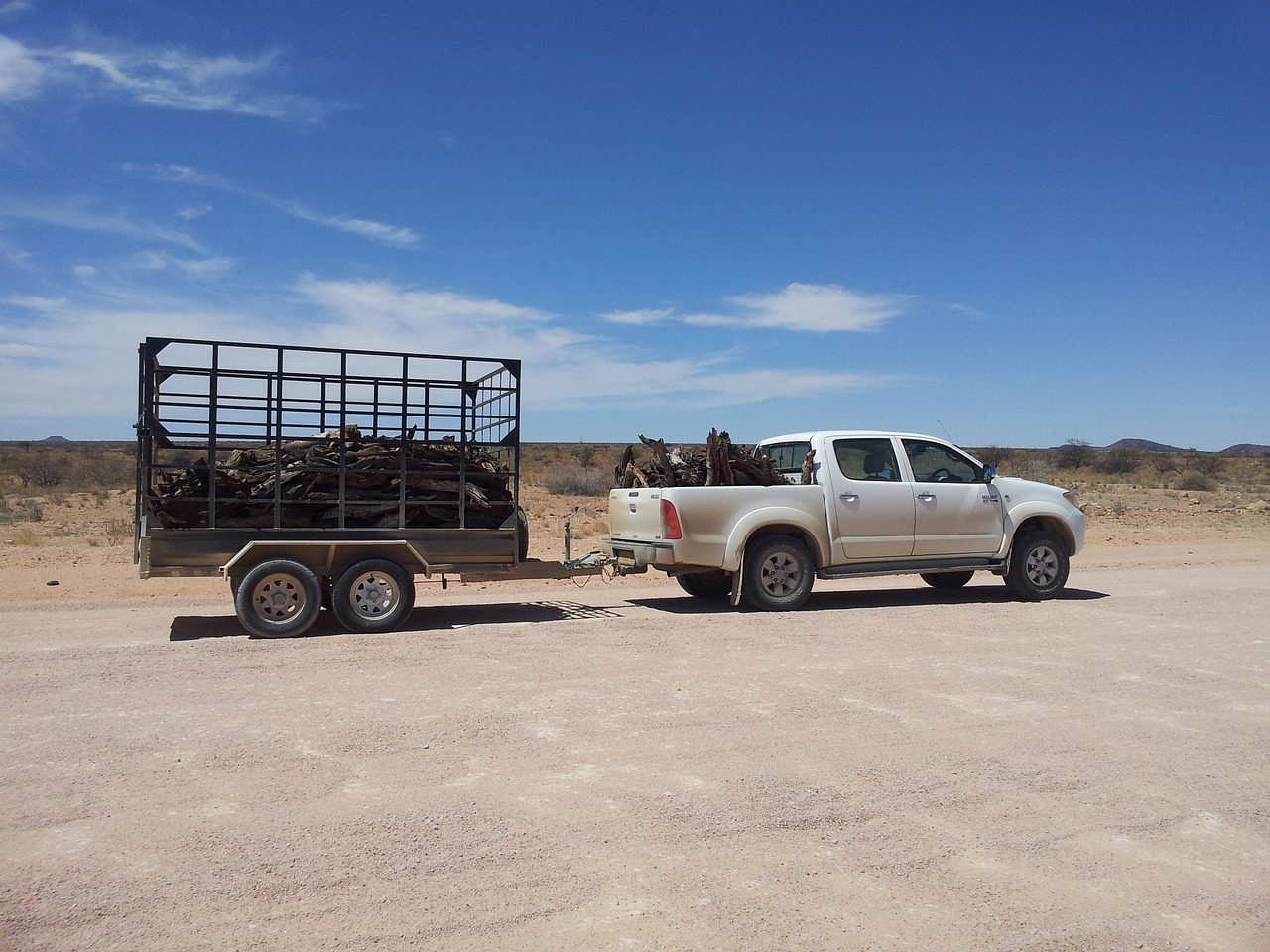 pick-up tractant une remorque chargée de bois sur une piste