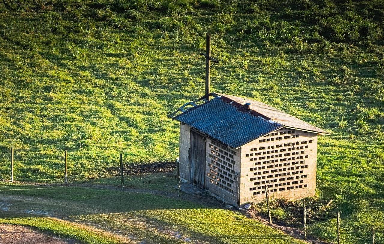 Petit local de rangement en parpaings posé au pied d'un terrain en pente