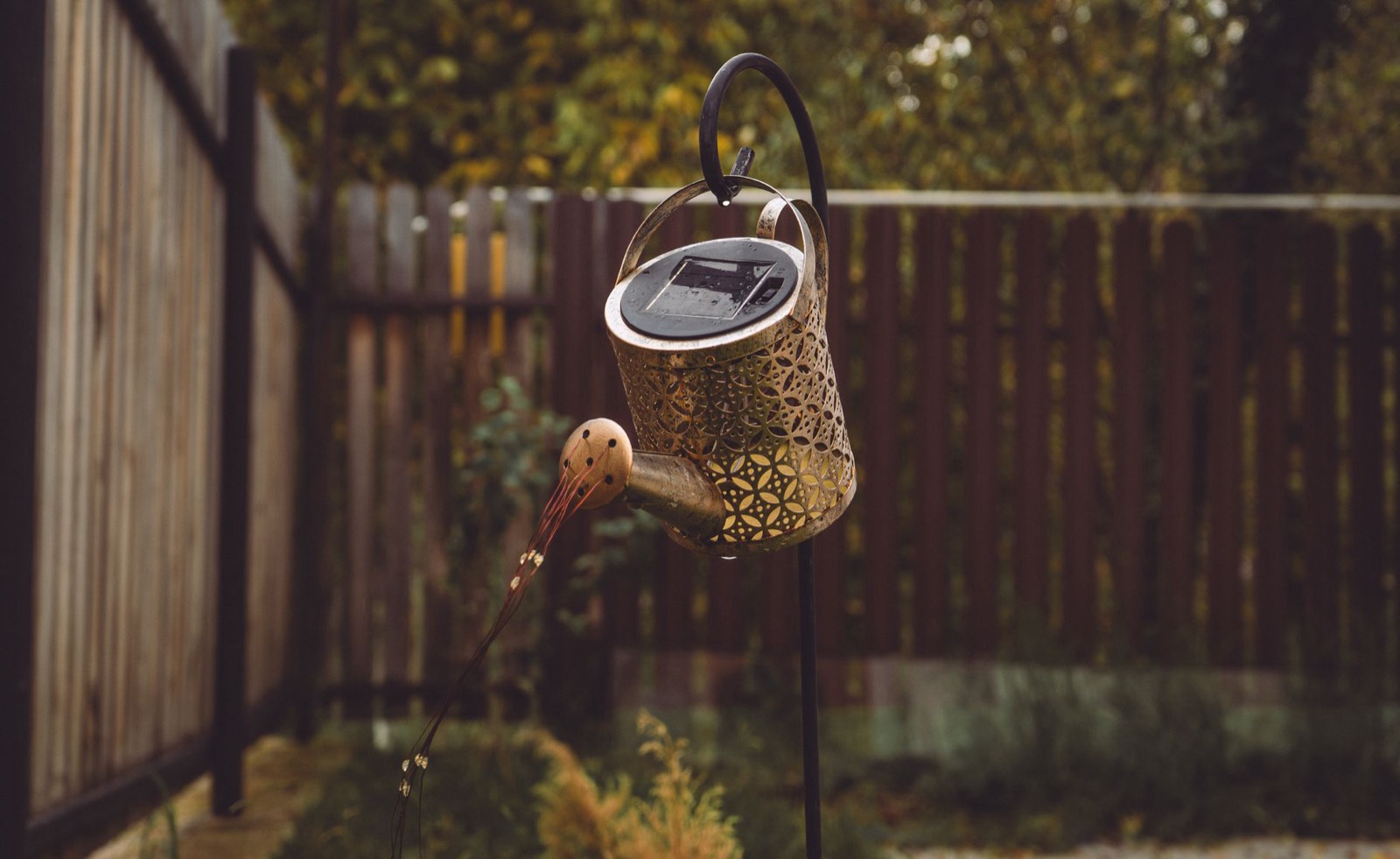 borne d'éclairage solaire design installée près d'un potager en bois